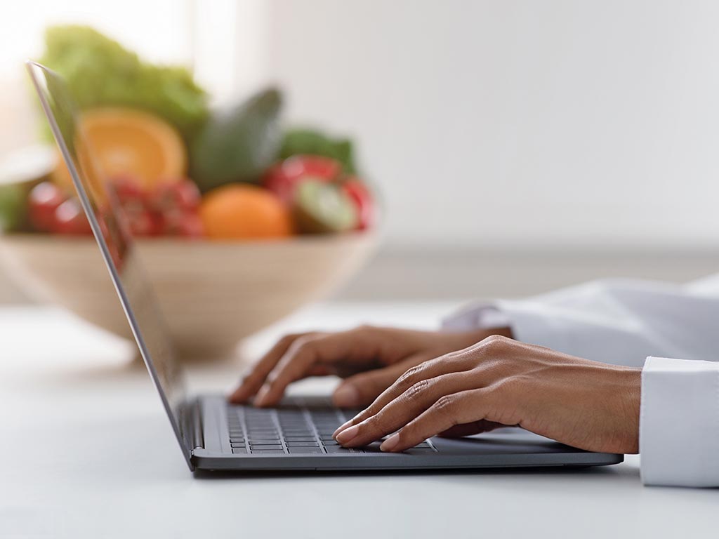 Black nutritionist working on laptop at office