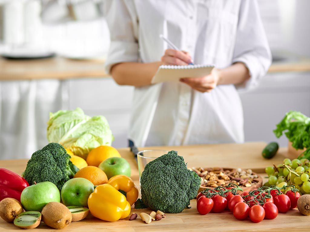cropped young woman nutritionist standing near table full of healthy products in office